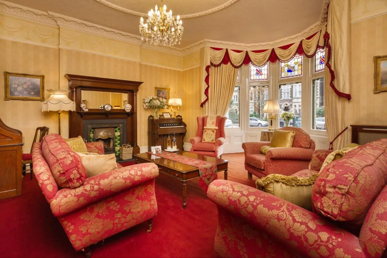 a living room with pink furniture and a fireplace at Lincoln House Private Hotel in Cardiff